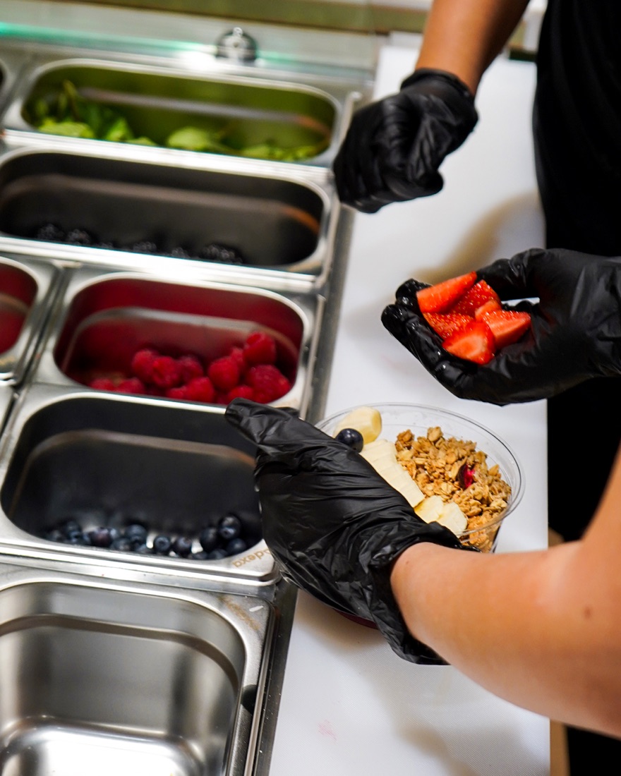 Our team adding fresh strawberries to an açaí bowl